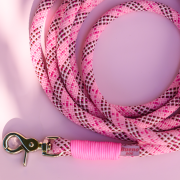 Detal smyczy Tartan Pink z różową owijką i złotym karabińczykiem na różowym tle