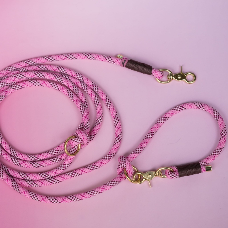 Smycz przepinana Tartan Pink z brązowymi owijkami i złotymi okuciami na różowym tle